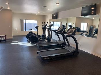 A row of treadmills in a gym with a large mirror on the wall